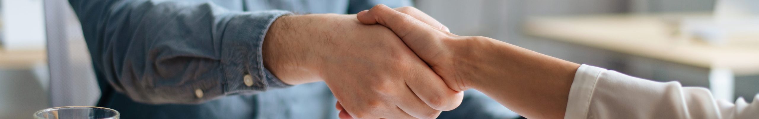 Cropped view of human resources manager shaking hands with successful vacancy applicant at office, closeup. Unrecognizable headhunting specialist welcoming new employee into company team